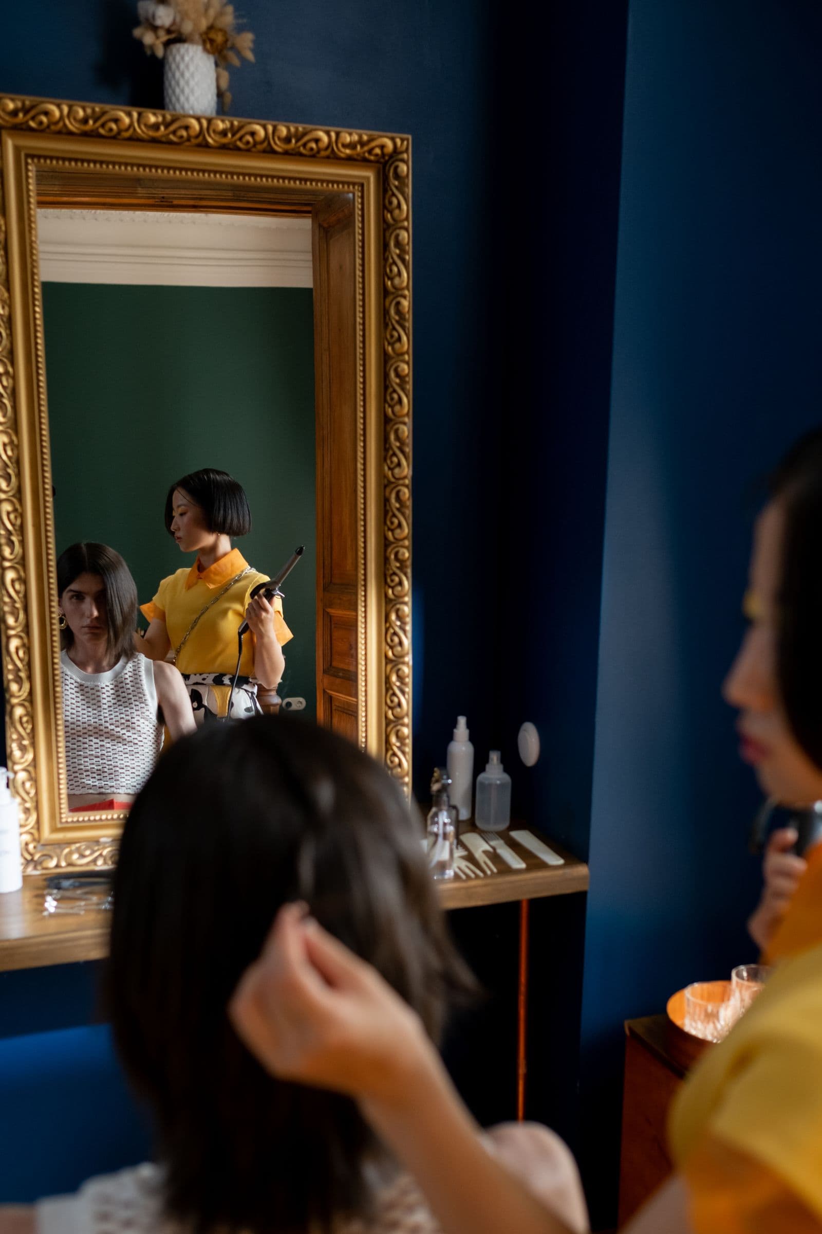 Stylist working on a client's hair in front of a mirror